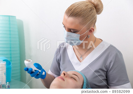 The cosmetologist adjusts the power of the device for galvanic massage. The cosmetologist adjusts the power of the device for galvanic massage. 89382099