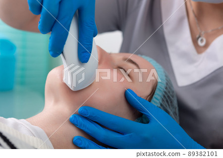 Young woman receiving electric galvanic anti-aging face spa massage at beauty salon. Young woman receiving electric galvanic anti-aging face spa massage at beauty salon. 89382101