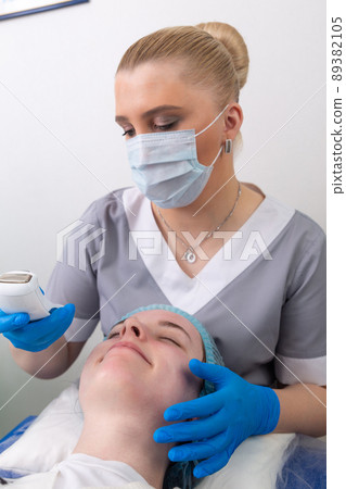 The cosmetologist adjusts the power of the device for galvanic massage. The cosmetologist adjusts the power of the device for galvanic massage. 89382105