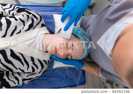 Young woman receiving electric galvanic anti-aging face spa massage at beauty salon. Young woman receiving electric galvanic anti-aging face spa massage at beauty salon. 89382106