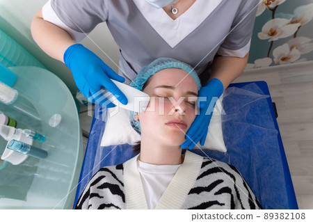 Young woman receiving electric galvanic anti-aging face spa massage at beauty salon. Young woman receiving electric galvanic anti-aging face spa massage at beauty salon. 89382108