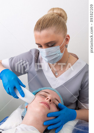 Young woman receiving electric galvanic anti-aging face spa massage at beauty salon. 89382109