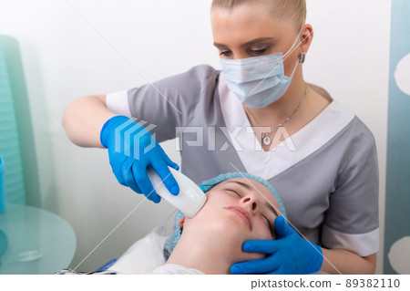 Young woman receiving electric galvanic anti-aging face spa massage at beauty salon. Young woman receiving electric galvanic anti-aging face spa massage at beauty salon. 89382110
