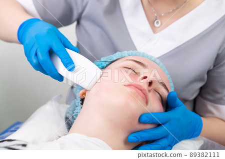Young woman receiving electric galvanic anti-aging face spa massage at beauty salon. 89382111