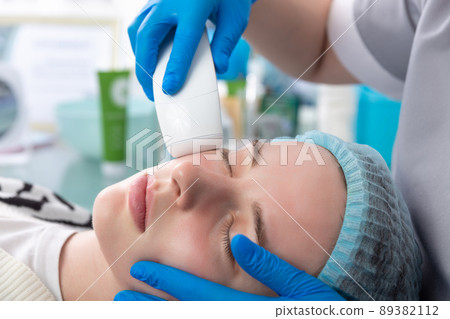 Young woman receiving electric galvanic anti-aging face spa massage at beauty salon. Young woman receiving electric galvanic anti-aging face spa massage at beauty salon. 89382112