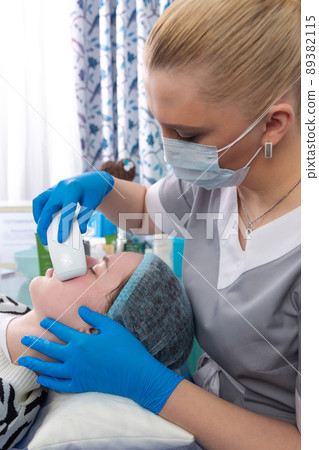 Young woman receiving electric galvanic anti-aging face spa massage at beauty salon. 89382115