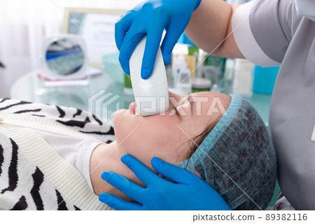 Young woman receiving electric galvanic anti-aging face spa massage at beauty salon. Young woman receiving electric galvanic anti-aging face spa massage at beauty salon. 89382116
