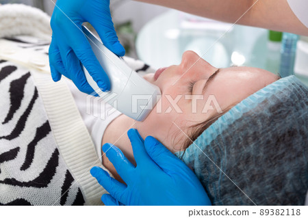 Young woman receiving electric galvanic anti-aging face spa massage at beauty salon. Young woman receiving electric galvanic anti-aging face spa massage at beauty salon. 89382118