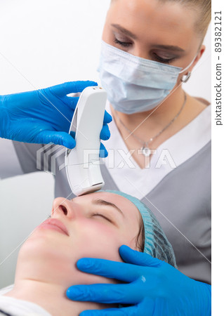 Young woman receiving electric galvanic anti-aging face spa massage at beauty salon. 89382121