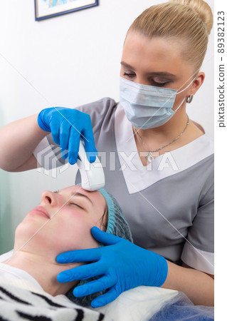 Young woman receiving electric galvanic anti-aging face spa massage at beauty salon. 89382123