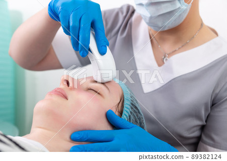 Young woman receiving electric galvanic anti-aging face spa massage at beauty salon. Young woman receiving electric galvanic anti-aging face spa massage at beauty salon. 89382124