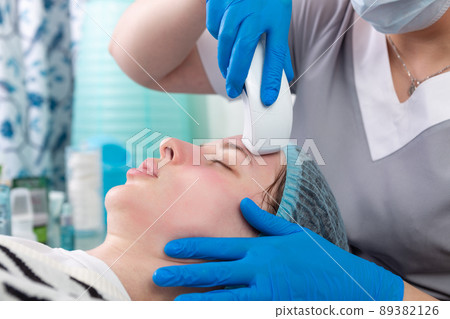 Young woman receiving electric galvanic anti-aging face spa massage at beauty salon. 89382126