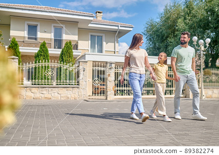 A young cute family walking in the street A young cute family walking in the street 89382274