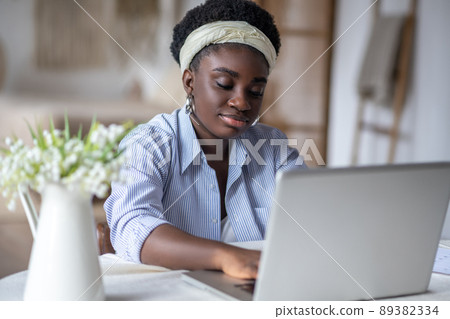 African american woman sitting at the table and working on a laptop African american woman sitting at the table and working on a laptop 89382334