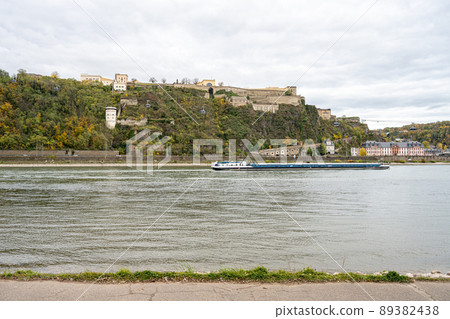 German corner, Koblenz were Rhein and Mosel meet. A river barge in the foreground with the fortress Ehrenbreitstein in the background 89382438