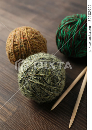 Multi colored balls of yarn with knitting needles on a wooden background 89382992