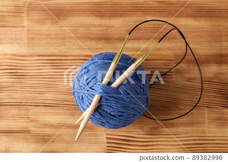 Blue ball of yarn with knitting needles on a light wooden table Blue ball of yarn with knitting needles on a light wooden table 89382996