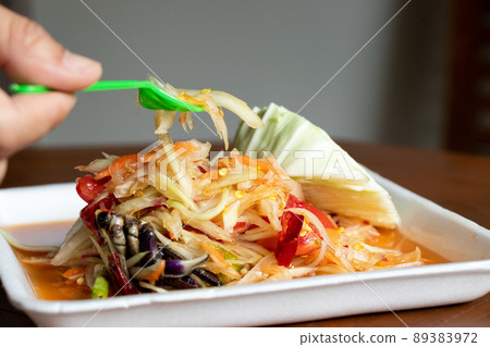 Female hand hold fork with Papaya salad, Thai food name Som Tum, on white foam plate 89383972