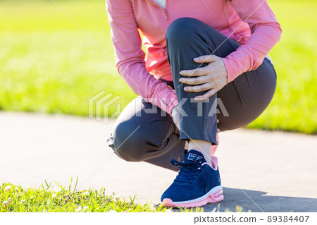 A middle-aged woman holding a calf that hurt while exercising A middle-aged woman holding a calf that hurt while exercising 89384407