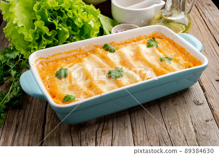 Cannelloni with filling of ground beef, tomatoes, baked with bechamel tomato sauce, side view, old dark wooden background 89384630