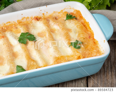 Cannelloni with filling of ground beef, tomatoes, baked with bechamel tomato sauce, side view,  89384723