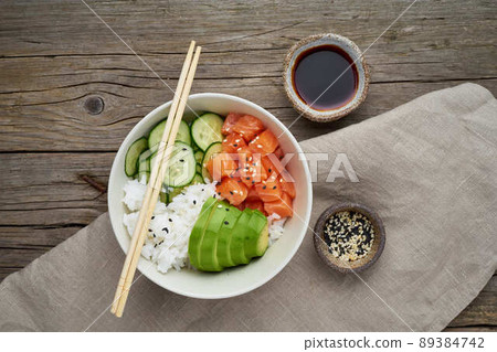 Salmon poke bowl with fresh fish, rice, cucumber, avocado with black and white sesame Salmon poke bowl with fresh fish, rice, cucumber, avocado with black and white sesame 89384742
