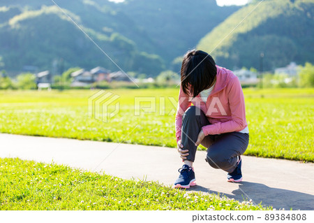 A middle-aged woman holding a calf that hurt while exercising 89384808