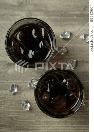 Glass of cola and ice on gray textured table 89385604