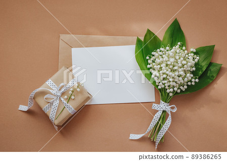 Lily of the valley and empty notepad with text copy space on beige background 89386265