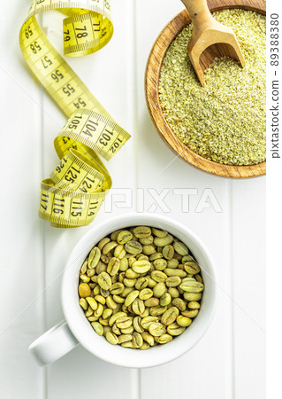 Ground green coffee and unroasted coffee beans on white table. 89388380