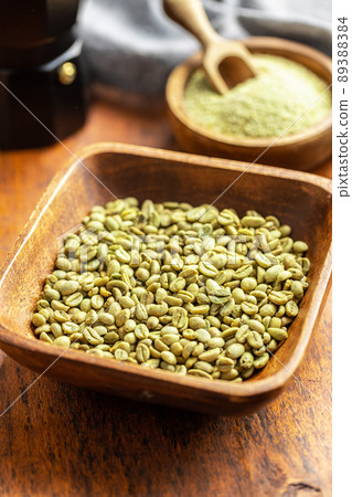 Unroasted green coffee beans in wooden bowl. 89388384