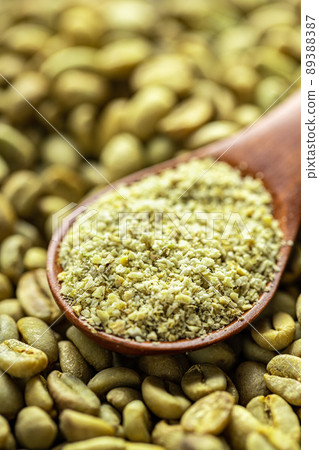 Ground green coffee in a scoop and unroasted coffee beans. Ground green coffee in a scoop and unroasted coffee beans. 89388387