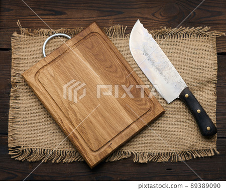 Large kitchen knife on an empty wooden cutting board, top view 89389090