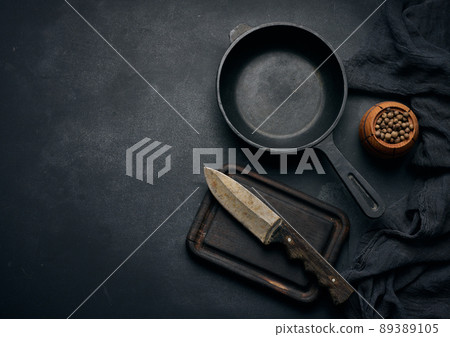 Empty round cast iron frying pan with wooden handle on black table, top view 89389105
