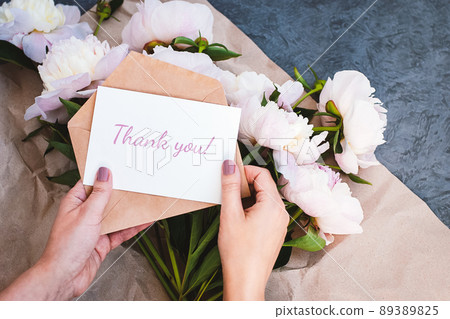Thank you card in hands, message, envelope, pink peony flowers bouquet 89389825