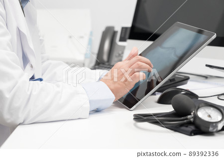 Doctor using his tablet computer at work 89392336