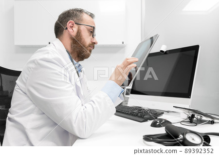 Doctor using his tablet computer at work 89392352