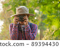 Asian man holding a camera with both hands.man wearing a hat taking pictures,copy space 89394430