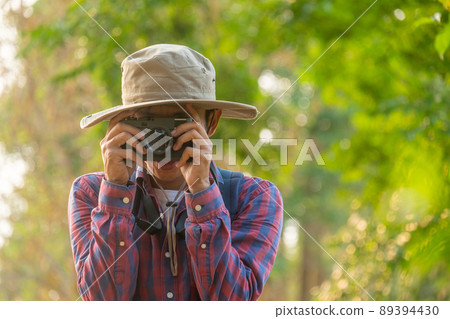 Asian man holding a camera with both hands.man wearing a hat taking pictures,copy space Asian man holding a camera with both hands.man wearing a hat taking pictures,copy space 89394430