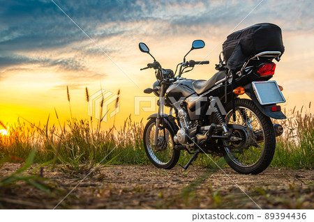 Black retro motorcycle with backpack parked outdoors. Black retro motorcycle with backpack parked outdoors. 89394436