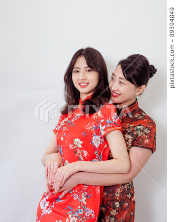 Portrait of mature asian mother hugging with her asian daughter on white background(Both wearing traditional cheongsam qipao). Portrait of mature asian mother hugging with her asian daughter on white background(Both wearing traditional cheongsam qipao). 89394849