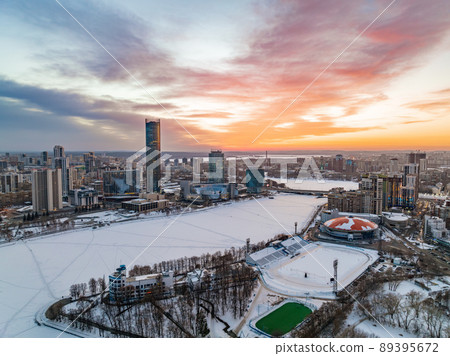 Yekaterinburg aerial panoramic view in Winter at beautiful pink and orange sunset. Yekaterinburg city and pond in winter. Yekaterinburg aerial panoramic view in Winter at beautiful pink and orange sunset. Yekaterinburg city and pond in winter. 89395672