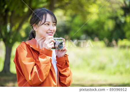 Young woman taking hobby photos outdoors with a retro film camera 89396912