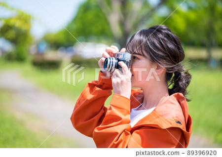 Young woman taking hobby photos outdoors with a retro film camera 89396920