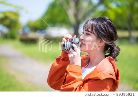 Young woman taking hobby photos outdoors with a retro film camera Young woman taking hobby photos outdoors with a retro film camera 89396921