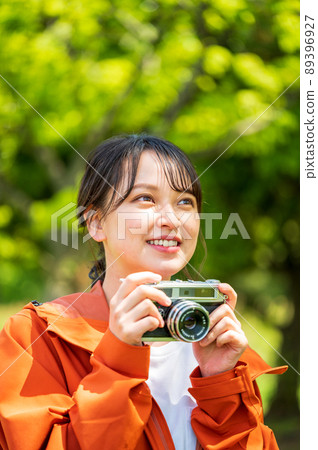 Young woman taking hobby photos outdoors with a retro film camera 89396927