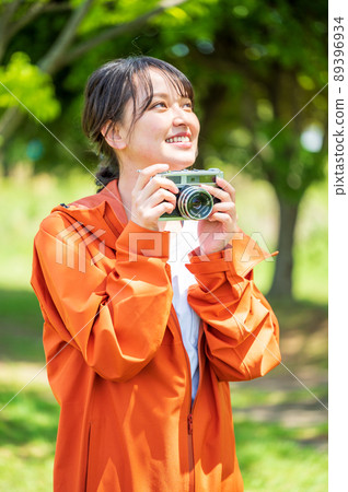Young woman taking hobby photos outdoors with a retro film camera Young woman taking hobby photos outdoors with a retro film camera 89396934