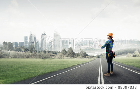 Woman in safety helmet standing on road Woman in safety helmet standing on road 89397838