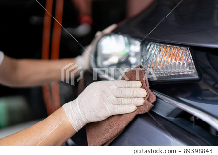 Asian workman wiping a car with high quality microfiber cloth in garage. Professional car care workshop. 89398843