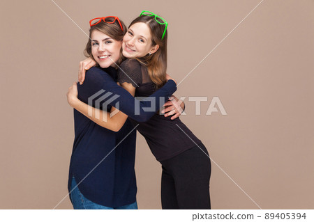 Happiness sisters embrace and toothy smiling. Studio shot 89405394